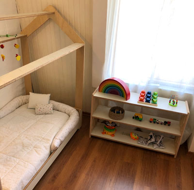 habitacion montessori cama y mueble medio de tres estantes